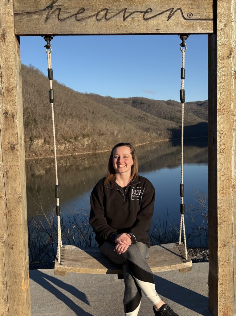 jessie gruskievich on a swing with a heaven banner with the mountains behind her